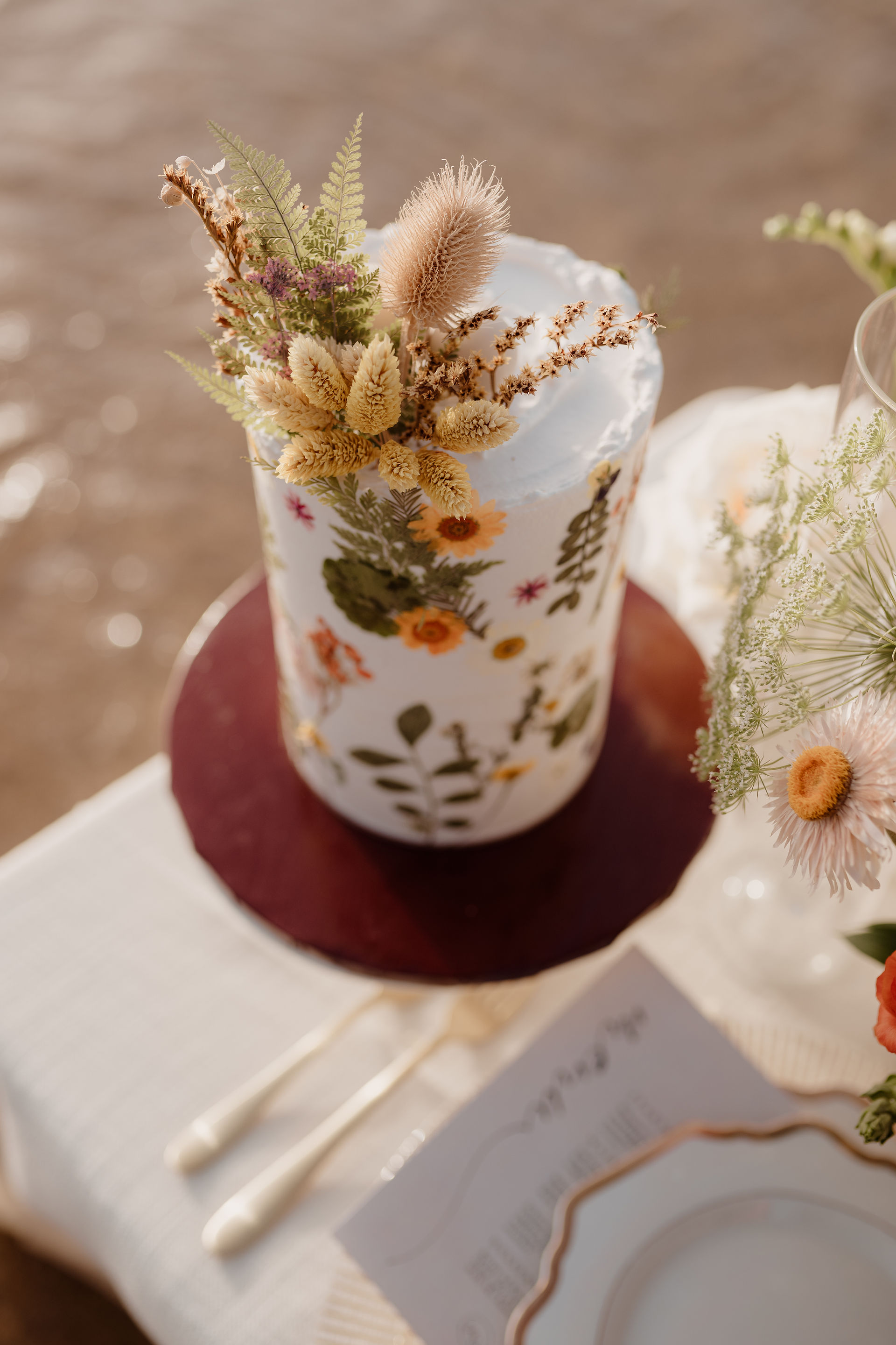 Cake decorated with dried flowers on a beachside table