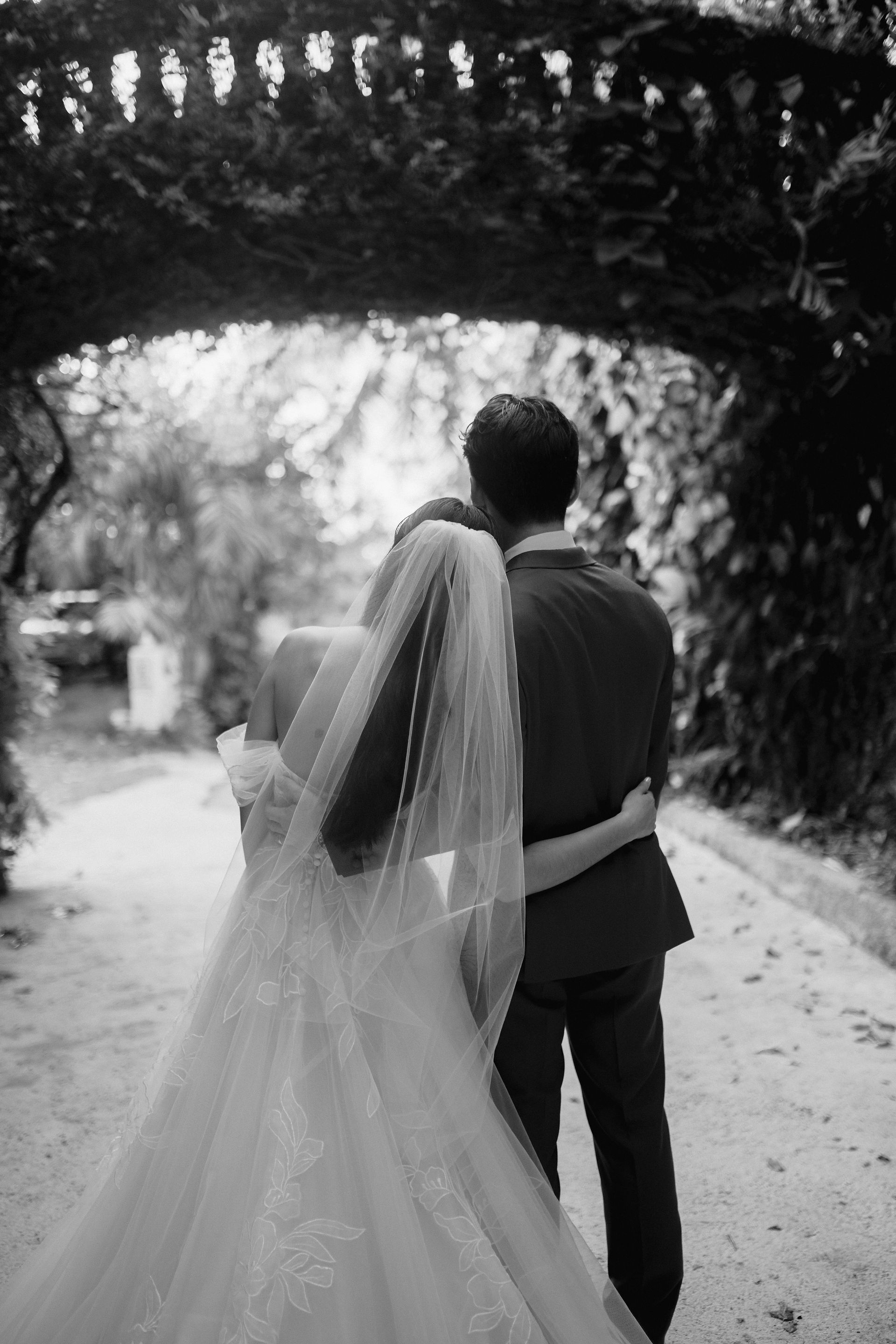 Bride and groom sharing a quiet moment under a green archway
