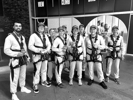 group of people in onesies and harnesses after climbing the Q1 building
