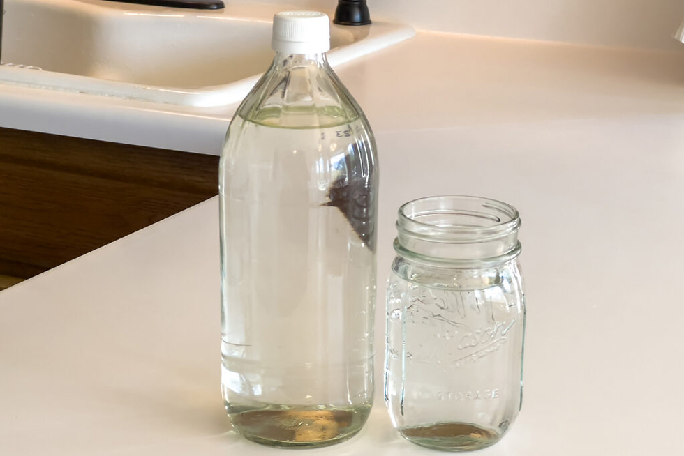 Glass bottle and Ball mason jar with water on a kitchen counter by a sink, with embossed Ball text.
