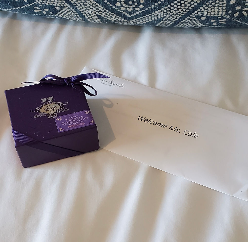 Welcome note and Vosges truffle collection gift box on a hotel bed, conveying a personalized luxury hospitality experience