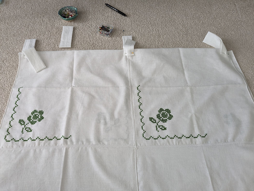 Curtain panel is laid out on the floor with the tabs pinned on at equal intervals