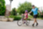 Cycling coach teaching a child to pedal her bike. 