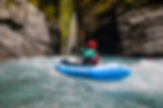 Packrafter paddling down white water rapid in upper Hokitika Gorge, surrounded by granite rock