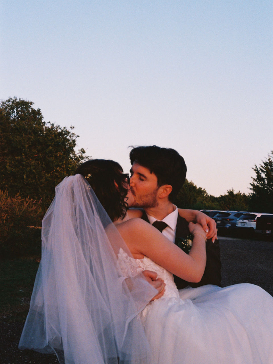groom holding bride in arms while they kiss