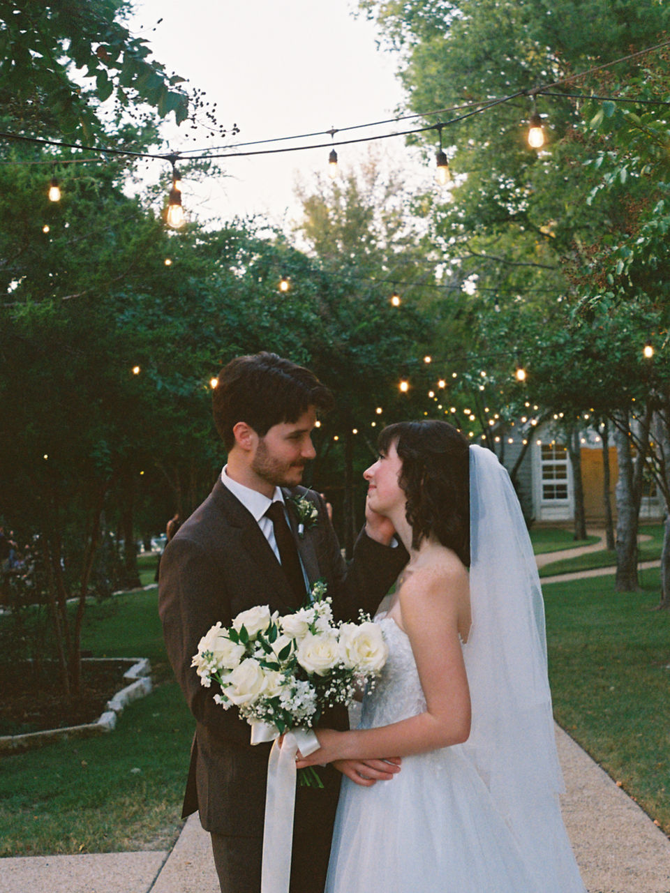 photograph of bride and groom smiling at one another, bride dressed in white gown with a veil