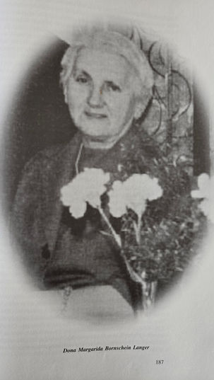 Retrato histórico e em formato oval de Dona Margarida Bornschein Langer. Ela olha para frente com semblante sereno, cabelos presos e veste uma blusa escura de gola alta. O fundo da fotografia é claro.