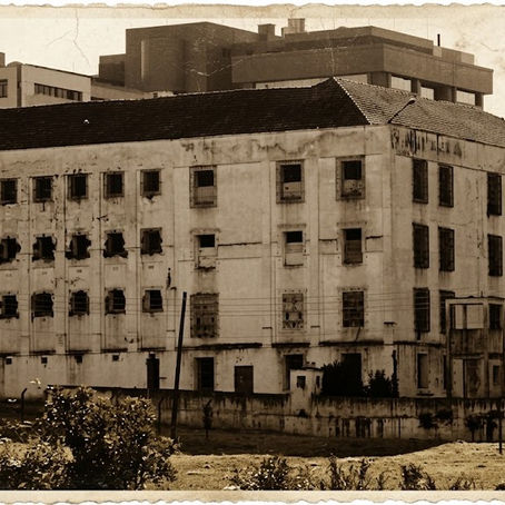 Fachada histórica do antigo Presídio do Ahú, em Curitiba, em fotografia com efeito envelhecido em tom sépia, exibindo paredes desgastadas e janelas com grades.