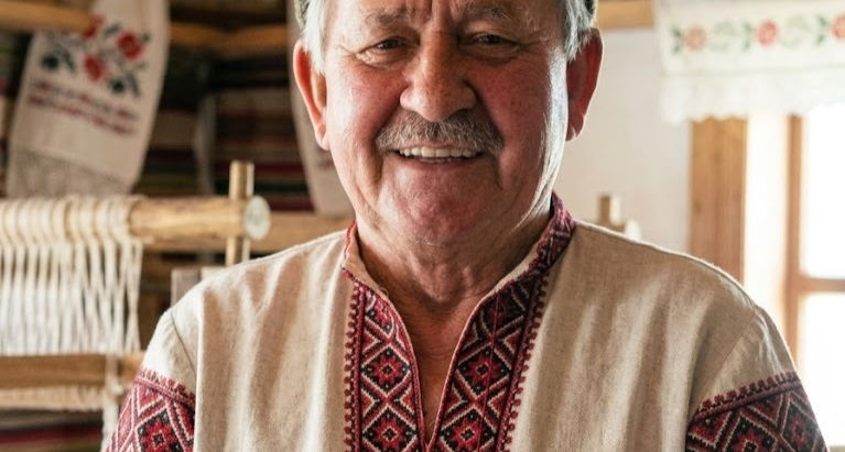 Fotografia de Emilio Gaudeda sorridente, vestindo uma tradicional camisa bordada ucraniana vyshyvanka e gorro de feltro.