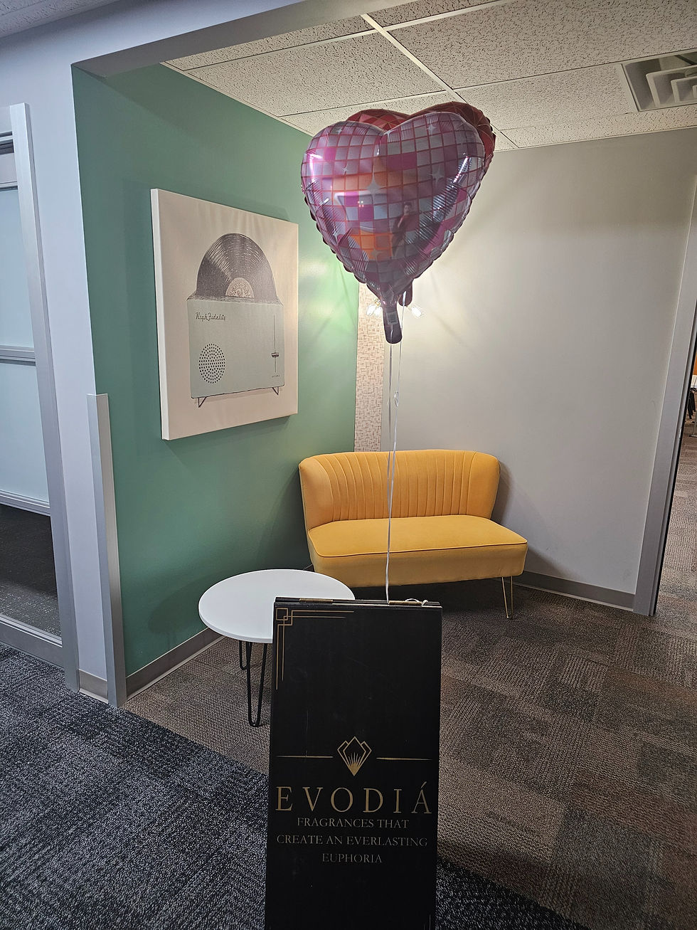 Heart balloon in office corner, near yellow couch, white table, and "EVODIÁ" sign. Vinyl record art on green wall. Calm atmosphere.