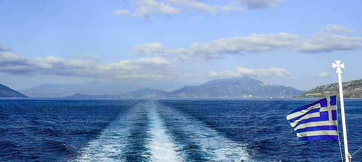 boat waves in a blue sea with a Greek flag