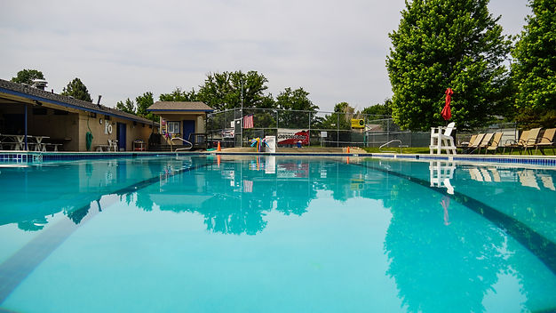 Picture of the swimming pool. There are picnic tables and a lifeguard chair