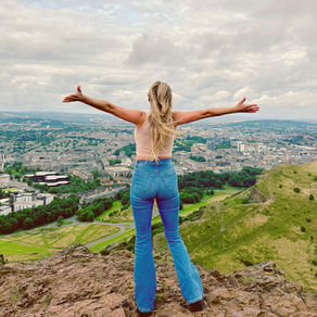 Woman standing overlooking Arthur's Seat in Edinburgh, Scotland. Arms open to the view, symbolizing freedom, clairty and self discovery.
