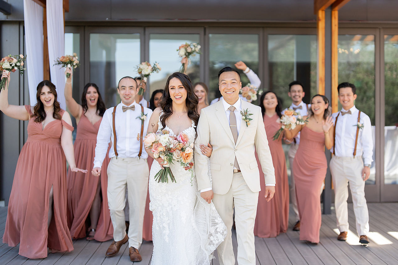 bride and groom walking with bridal party behind them