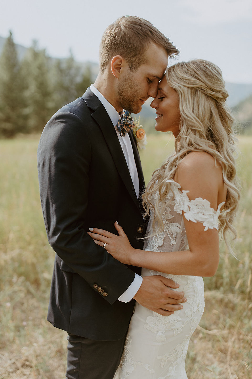 bride and groom embrace in field