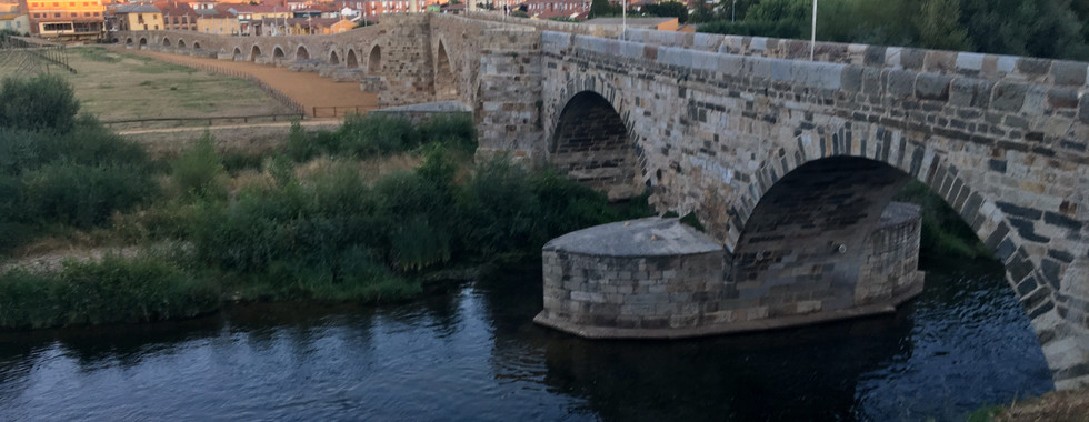 This is the impressive Gothic bridge over the Río Órbigo that is the site of a legendary medieval jousting competition. Don Suero de Quiñones, a wealthy Leonese knight, was rejected by the woman he loved. In his heartbreak, he locked his neck in an iron collar and swore he would not take it off until he defeated 300 knights in jousting. The call went out, and knights from all over the kingdom came in the Holy Year of 1434. Quiñones succeeded in his quest, freeing him from the torment of love. He took off the collar and made a pilgrimage to Santiago where he left a bejeweled bracelet, which can still be seen in the cathedral museum. The bridge became known as "El Paso Honroso" (the Honorable Pass).