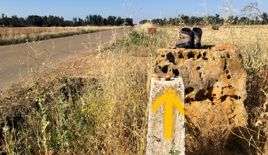 This is a view of a marker as well as some abandoned, worn out shoes left by a pilgrim.