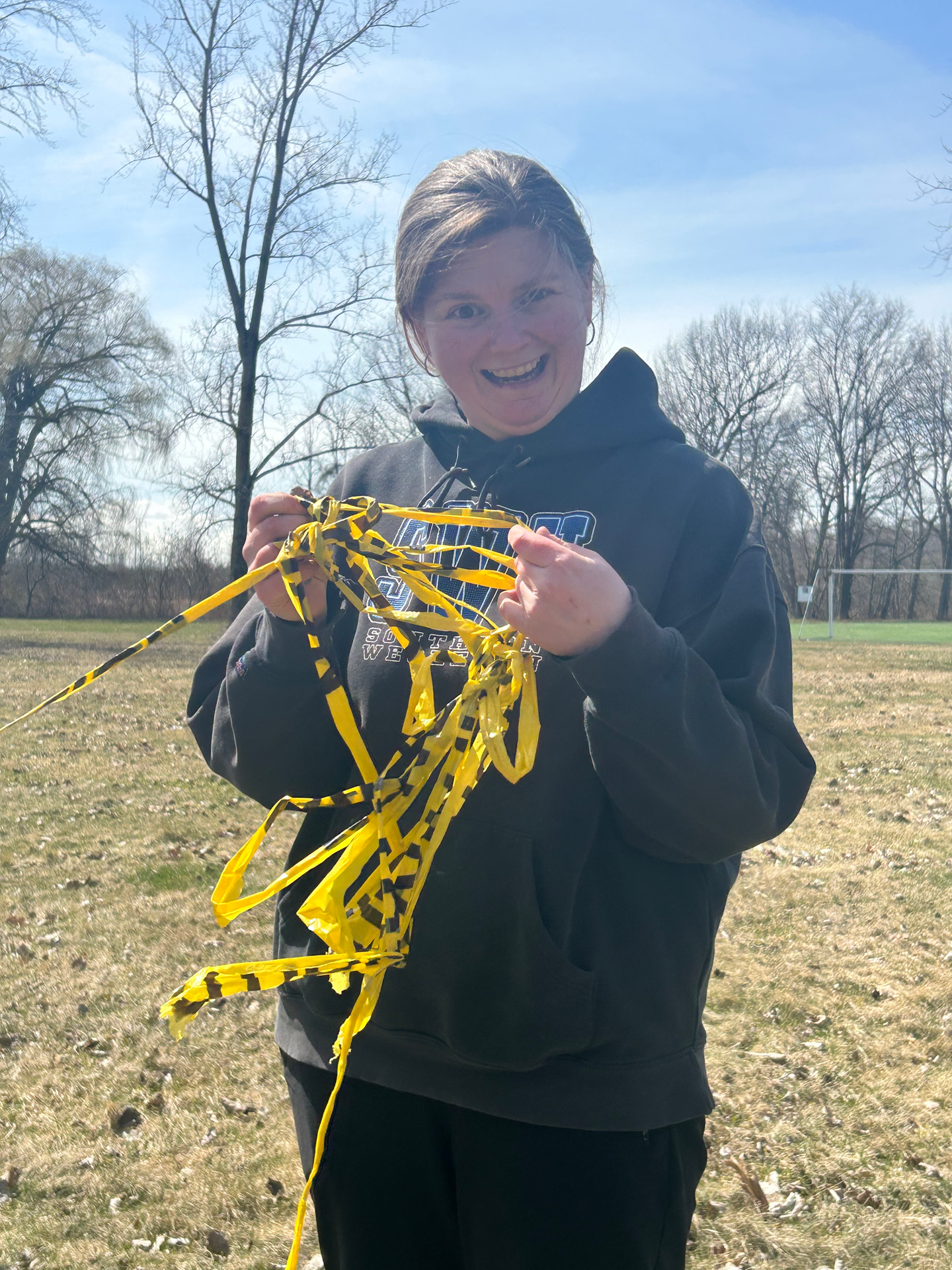 a woman wearing a sweatshirt that says ' ucsd ' on it holds a bunch of yellow ribbons