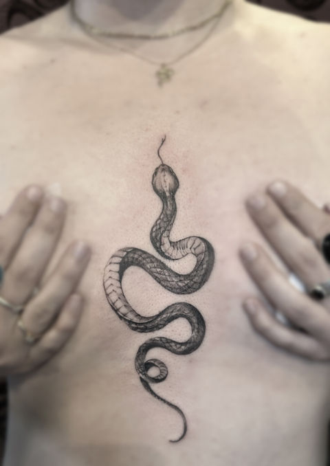 snake tattoo on chest with hands covering chest