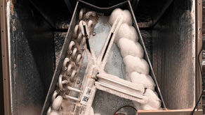 Frost-covered coils inside a metallic air conditioning unit, with icy buildup. The setting appears industrial, with textured metal surfaces.