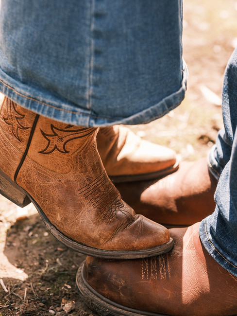 Detail of worn Red Wing boots and broken-in country boots side by side — authentic styling for a cou