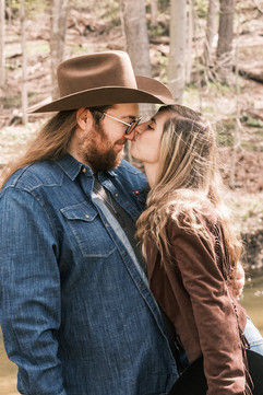 Couple laughing together in coordinated denim during a country-themed outdoor engagement session at Powder Mill Park, Rochester NY