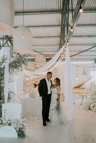 Bride and groom standing in front of a styled table with a welcome sign in the background