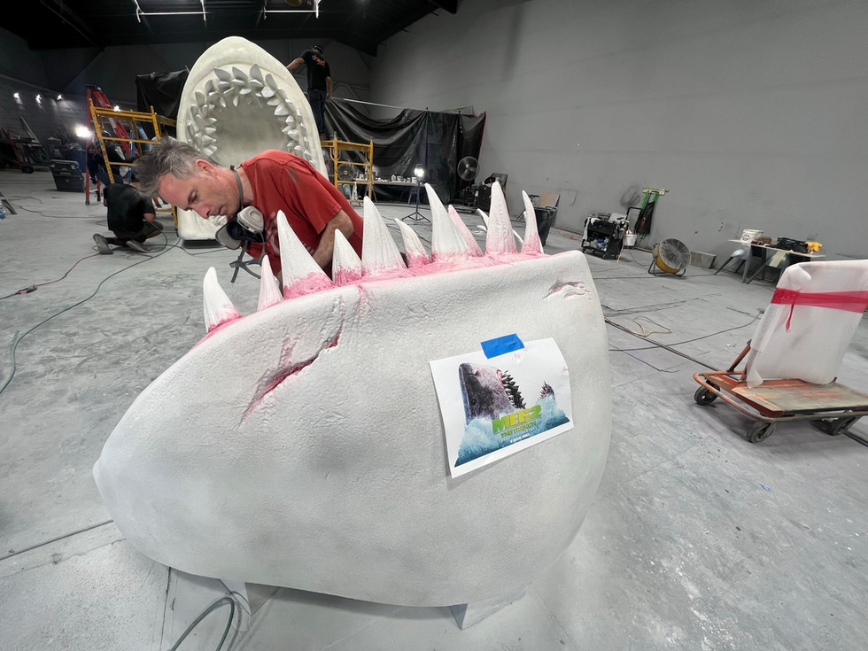 Experiential fabrication, scenic paint, sculpting, captivating, remarkable project, expert team, menacing Meg shark, intricate scenic paint work, artistry, detailed scenic design, awe-inspiring installation, experiential masterpiece, legendary Meg, face-to-face, thrill.