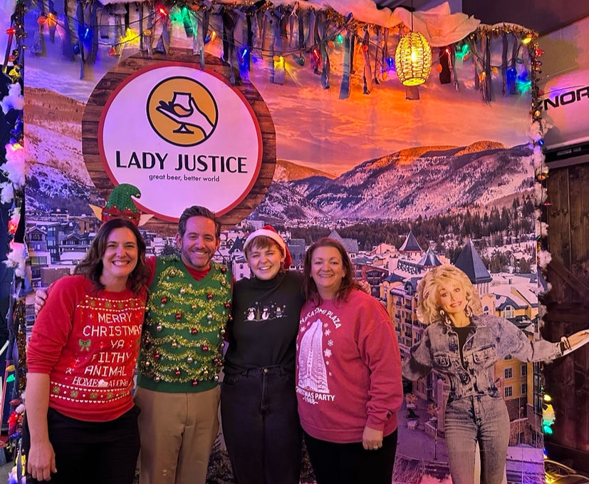 Second Wind Fund team poses wearing ugly Christmas sweaters for a fundraiser for youth suicide prevention