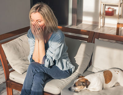 Frustrated nervous sad middle aged woman sitting on sofa, touching forehead, suffering fro