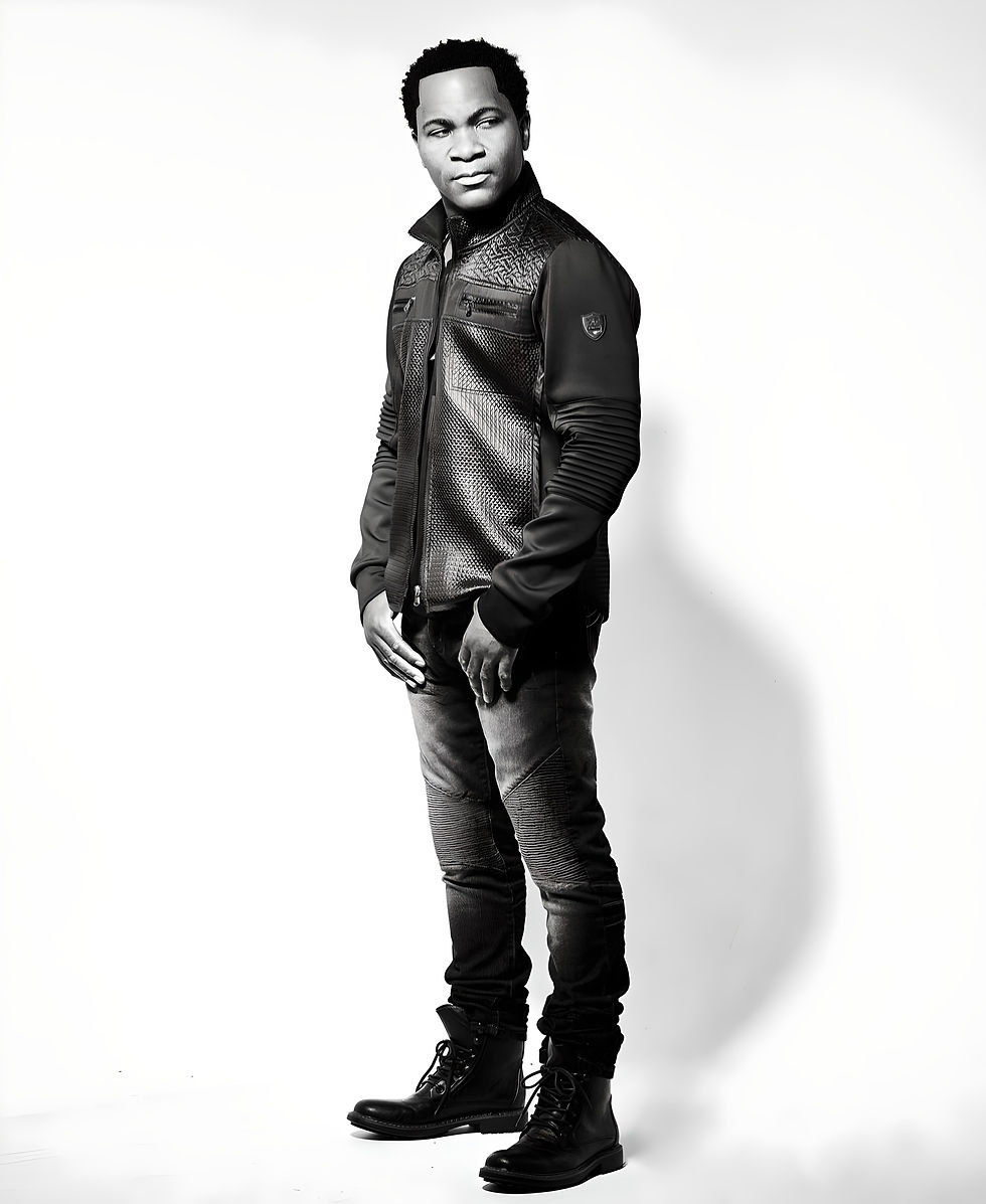 Aaron Bing in a textured jacket and jeans stands confidently against a white background. He wears dark boots, exuding a stylish and calm demeanor.
