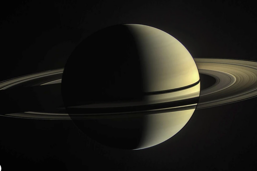 Saturn with rings visible against a dark space background. The planet is half-lit, showcasing a serene, celestial mood.