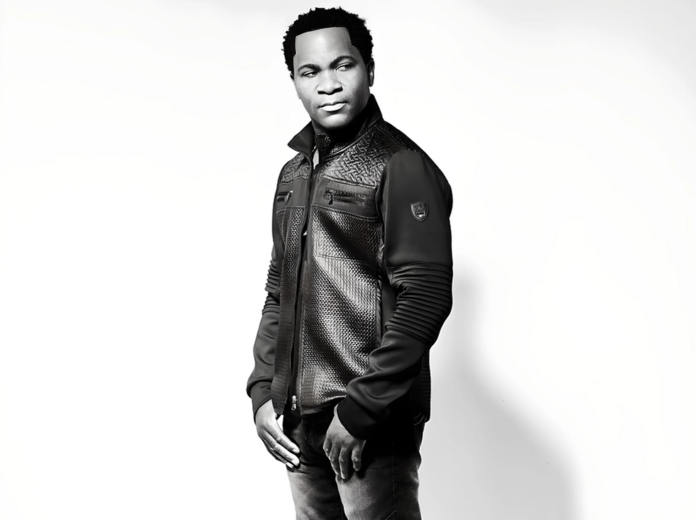 Aaron Bing in a textured black jacket stands confidently against a white background, looking to the side, with a neutral expression.