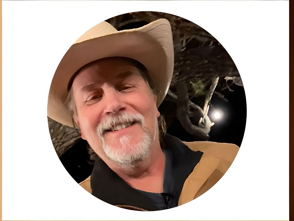 Man in a cowboy hat smiling at night under a tree with a full moon in the background. Wearing a tan jacket, cheerful mood.