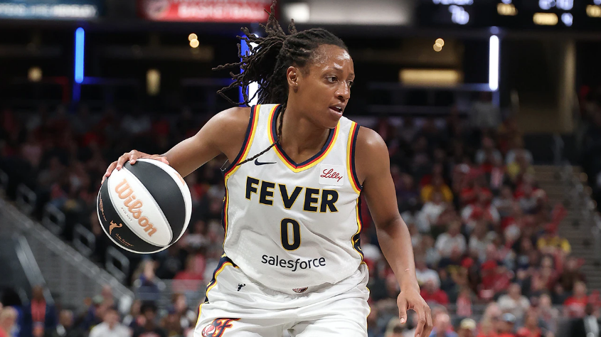 Indiana Fever player drives forward with focus during a game, showcasing skill and determination on the court.