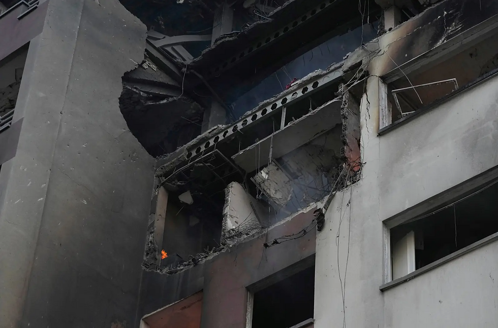 Damaged building exterior with exposed wires and a small flame on a balcony. The grays and blacks create a somber, burned appearance.