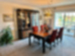 Luxurious dining room with a large wooden table, unique chandelier, and expensive silverware cabinet