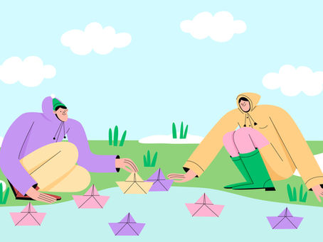 두 사람이 마주보고 웅덩이에 색색깔의 종이배를 띄우고 있다.