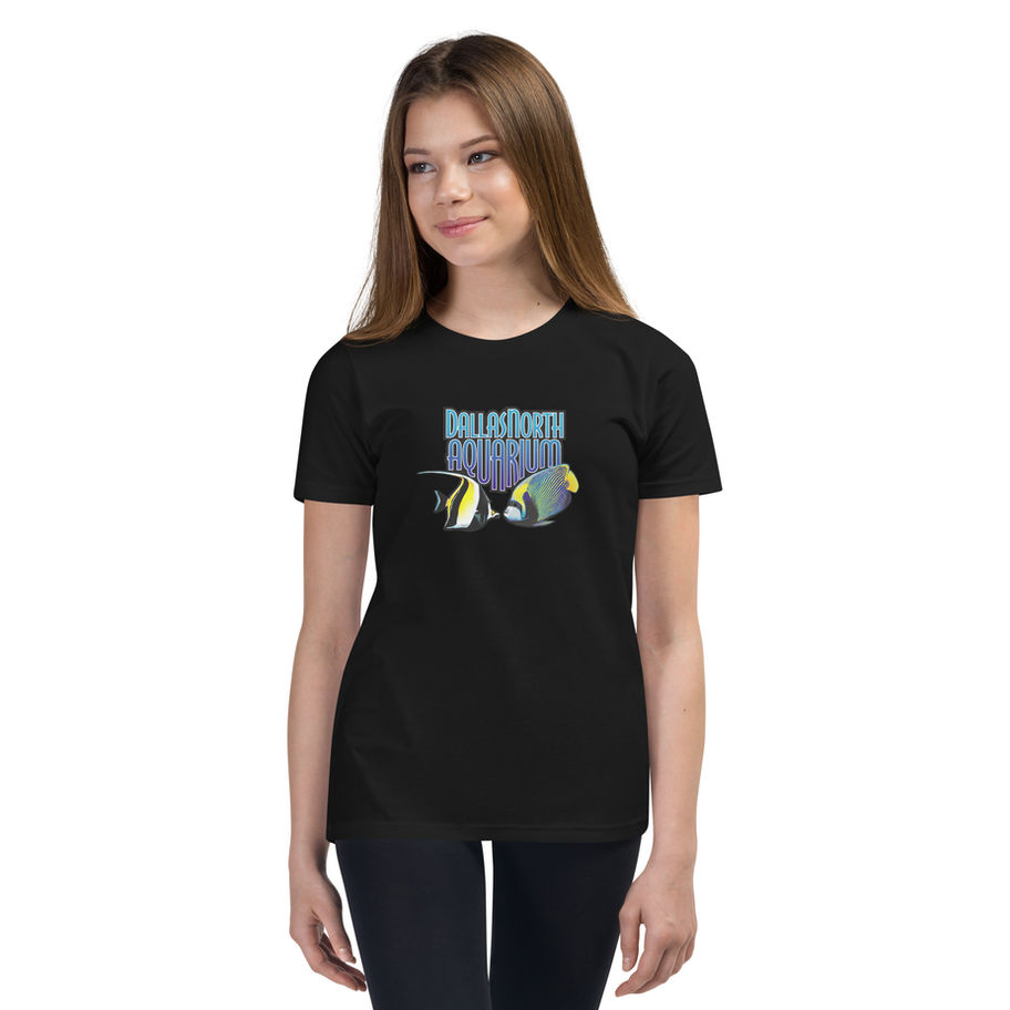 A young woman wearing a black Youth Short Sleeve T-Shirt with a graphic of two fish and the text DallasNorth Aquarium