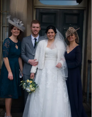 A bride and groom posing with their mothers