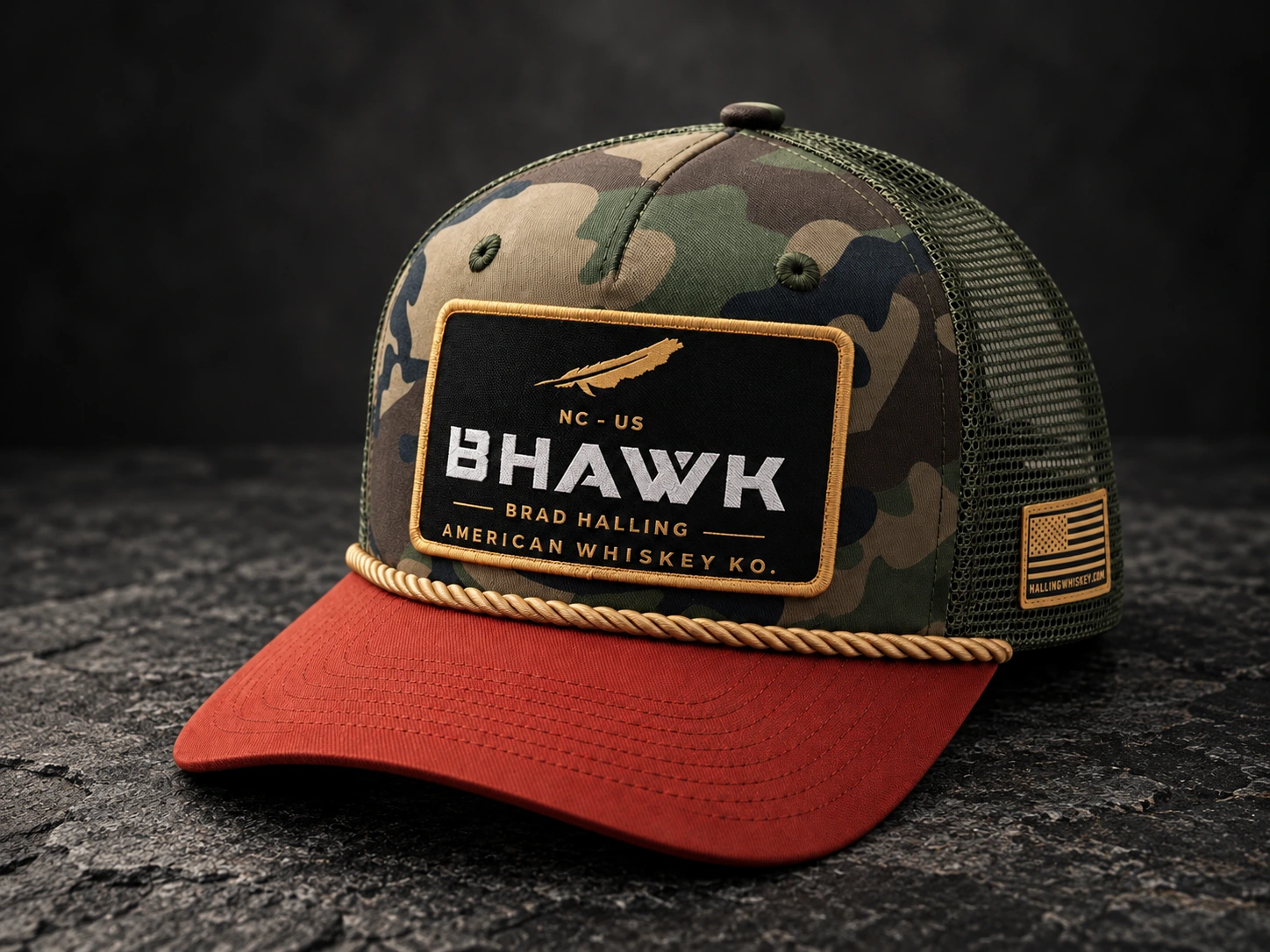 Camouflage custom hat with a red brim, fabric patch and gold rope on dark textured stone