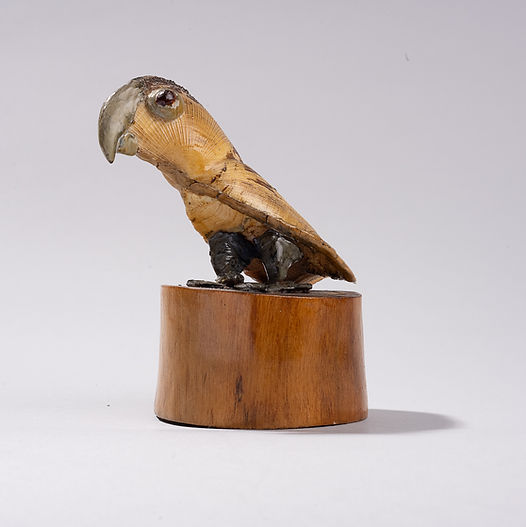 Shellfolk bird figure with a curved shell body and beak, standing on a wooden base, made from shells and natural materials.
