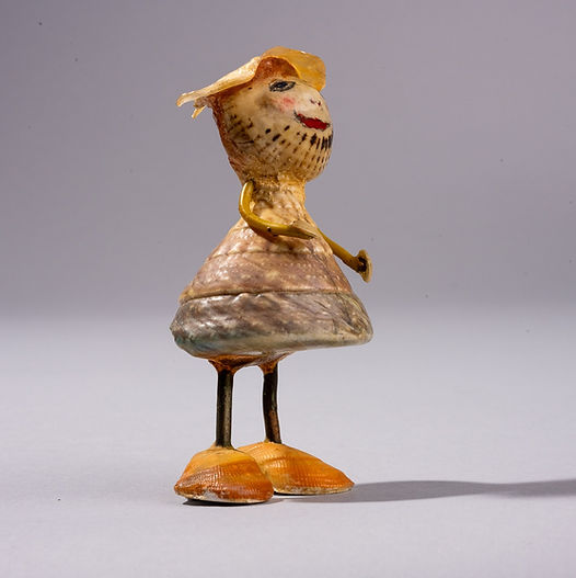 Shell figure wearing a structured shell dress with layered textures, small shell hat tilted on the head, slender legs ending in shell shoes, natural markings and slight imperfections visible on the shell surface.
