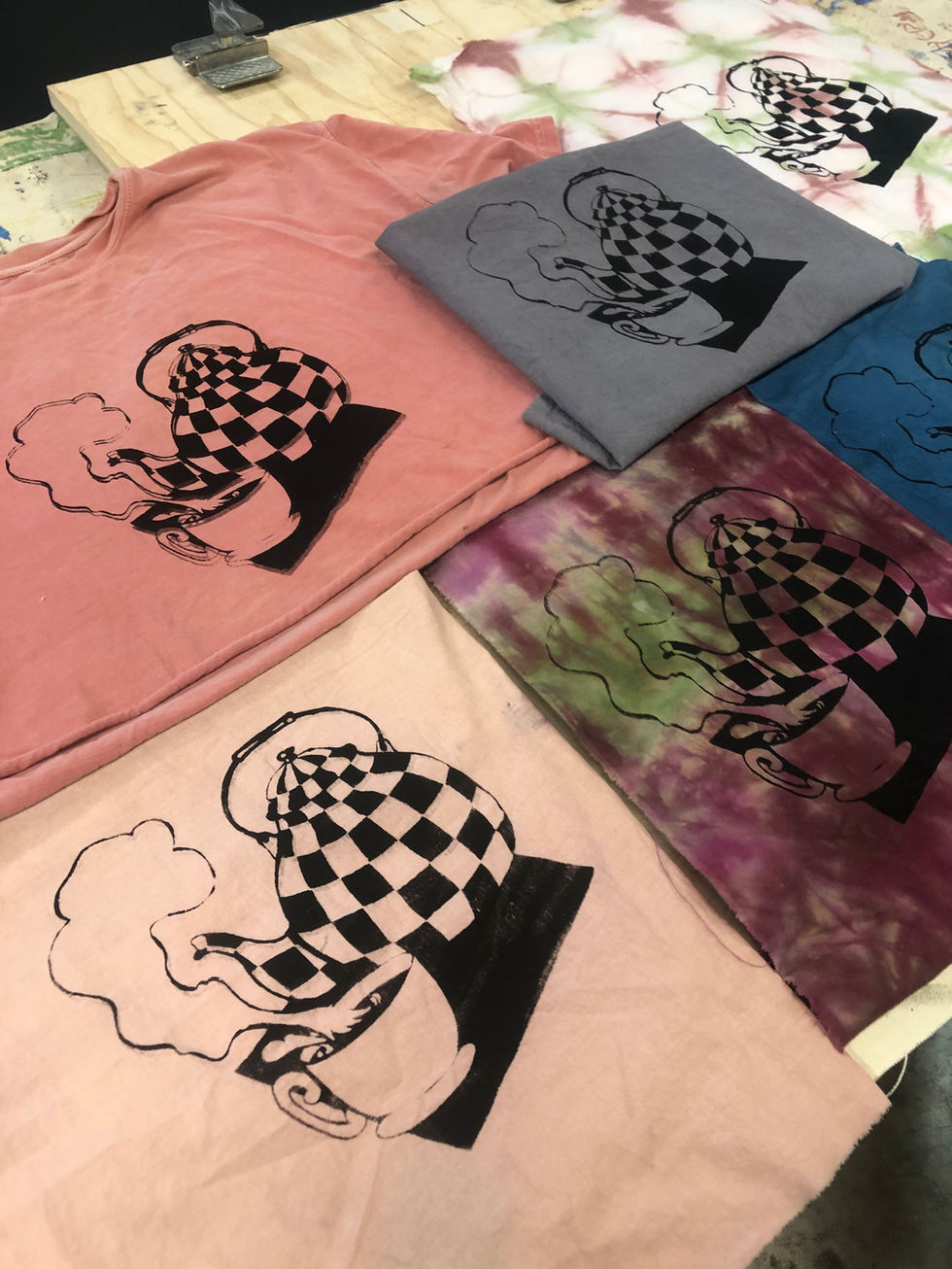 screen-prints on hand dyed fabrics of a checkered teapot and teacup with steam.