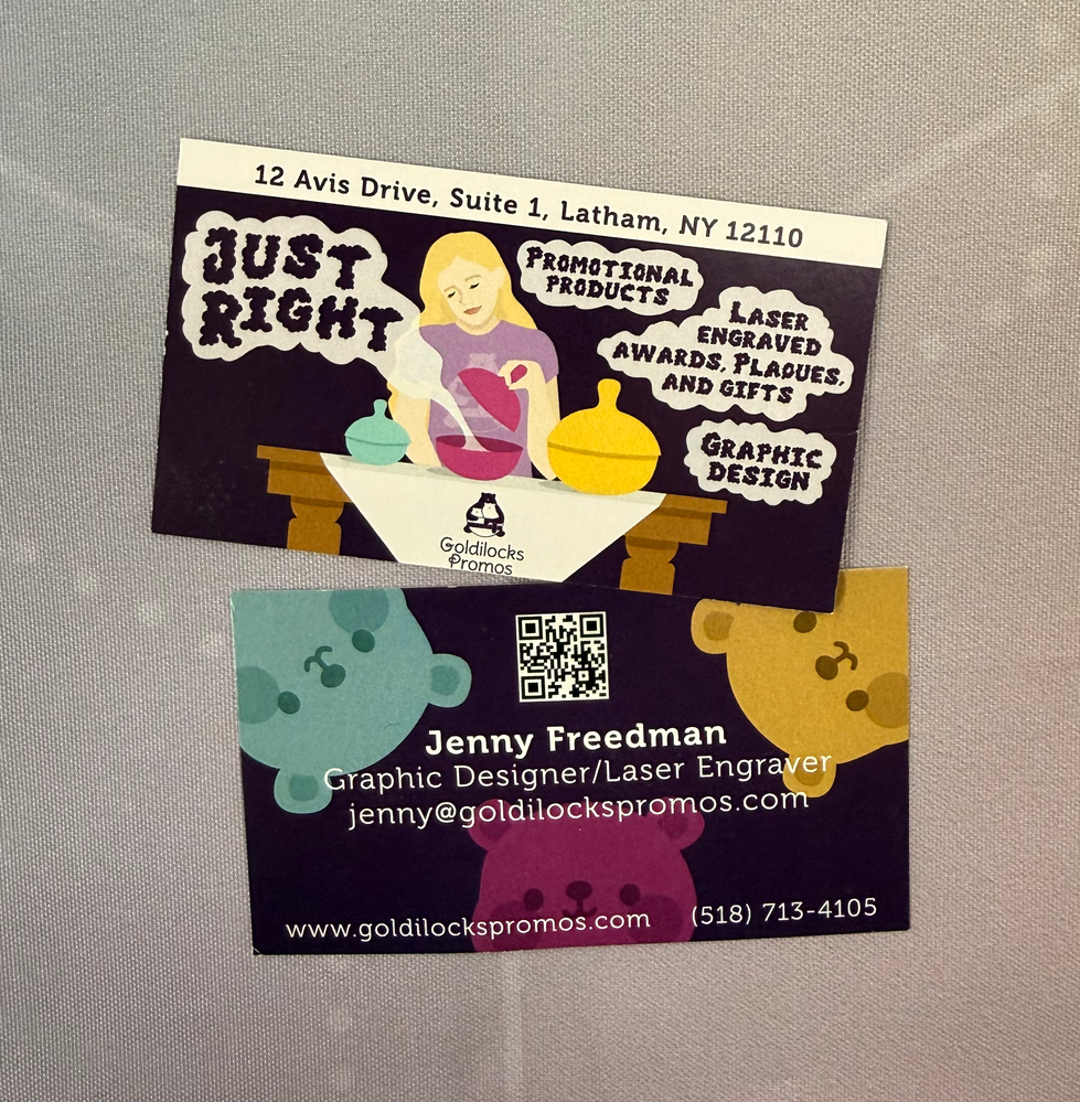 Business cards for promotional products, laser engraved plaques, awards and gifts, and graphic design. Shows goldilocks lifting a lid with steam that reads "Just Right" and the heads of 3 bears on the back.