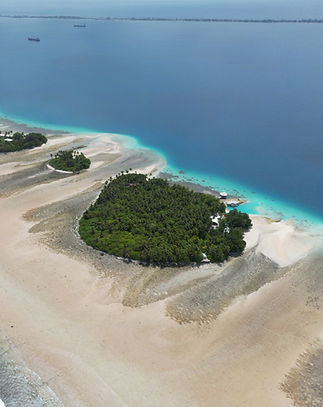 Aerial view of the private island of Bokanbotin Island Resort surrounded by turquoise water and coral reefs in the Marshall Islands