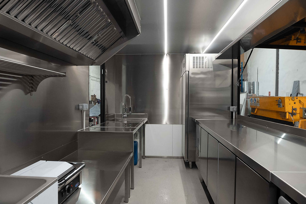 Cocina industrial de acero inoxidable, con fregadero y muebles brillantes. Ambiente moderno y limpio con iluminación blanca.