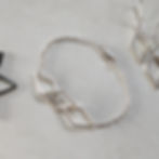 a ladies thin silver chain bracelet which has 3 big geometric rhombus shapes in the centre which have been linked together in a chain.