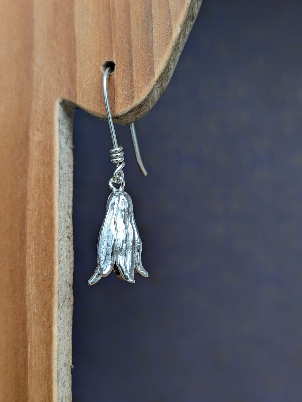 silver bluebell drop earrings displayed on a wooden earring stand