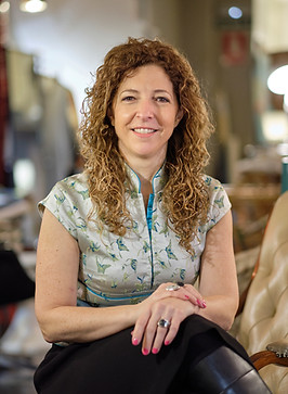 Foto de Andrea Caprarulo Pasquali, técnica de proyectos de Equala Iniciativas en Consultoría, sentada en un sillón, rodeada de muebles vintage en La Cabina Muebles, tienda de Pamplona.
